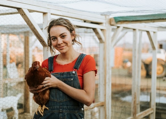 Jonge vrouw met bruine kip in haar handen