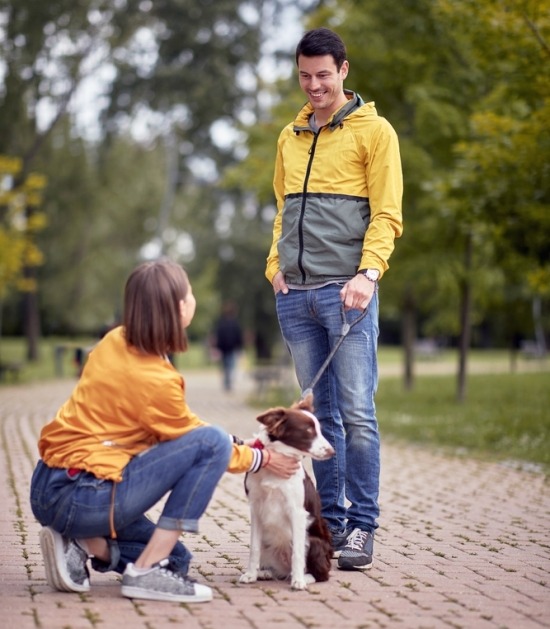 Man met hond praat met vrouw op straat 