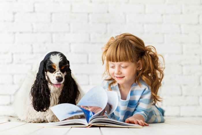 Meisje leest boek voor aan hond Meisje leest boek voor aan hond