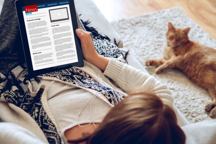 Vrouw leest tablet met kat naast zich